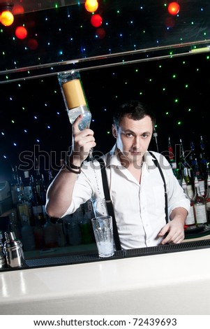 Bartender bartender is pouring a drink and looking at the camera Royalty-Free Stock Photo #72439693