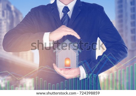 Businessman in suit holding home button on a virtual interface.,Real estate concept.