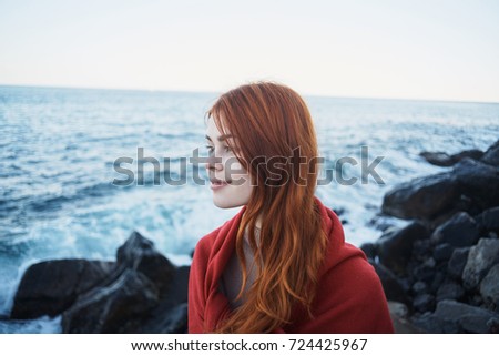 beautiful, young woman in a plaid basking in the background of the sea, evening                               