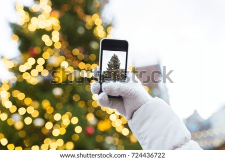 holidays, technology and people concept - hands with smartphone photographing christmas tree