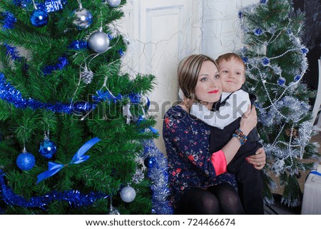 the boy and mother embrace and smile under the decorated Christmas tree. happiness and family values