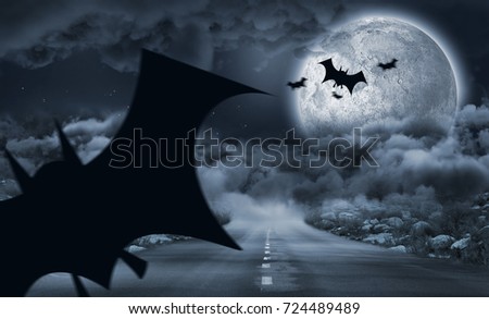 Digital image of silhouette bat against landscape of a road between stone in front of the moon 