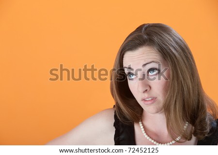 Caucasian woman on orange background looks up