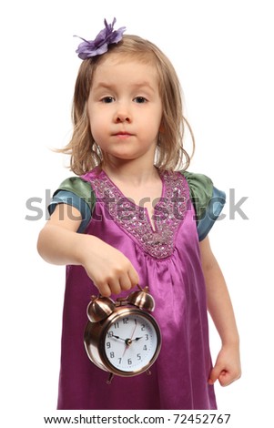 Little glamour girl in stylish dress shows time on round alarm clock
