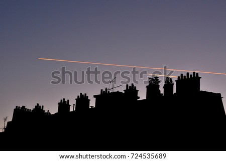 Early morning sunrise reflecting off of airplane contrails over apartment building in Paris France