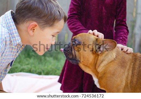 Happy kids playing with puppies in sunny day. Cute boy and girl with cheerful french bulldog pets.