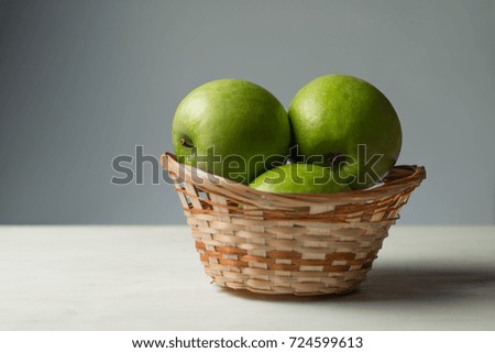 green apples in a basket, on a gray background