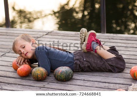 Boy lies with pumpkins on the river bank
