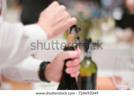 Blur image of man opening a wine bottle with corkscrew in a bar.