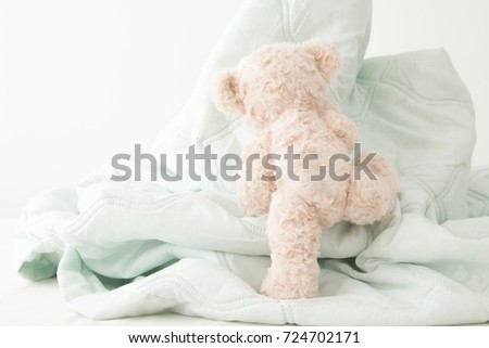 Teddy bear climbs on a pile of blankets, Naughty doll.