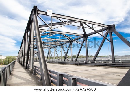 Steel bridge structure with Cycleway alongside it on beautiful cloudy, blue sky day.