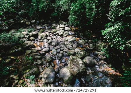 transparent quiet stream of a mountain river flows among the rocks in the shadow of the forest. Small waterfall in Sa-pan at Nan, Thailand