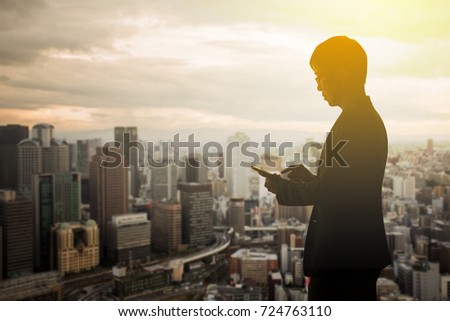 Silhouette businessman using smartphone with cityscape background
