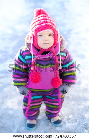 Cute toddler girl outdoors on a sunny winter day, walking, snowy day