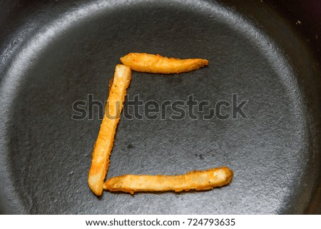 English character C is assembled by french fries in a cast iron pot.