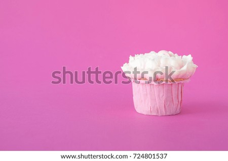 Pink cupcake with white whipped cream in form of flower on pink background. Picture for a menu or a confectionery catalog.