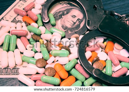 Financial crimes in medicine. Handcuffs, medicines and dollars on the table. Toned photo.
