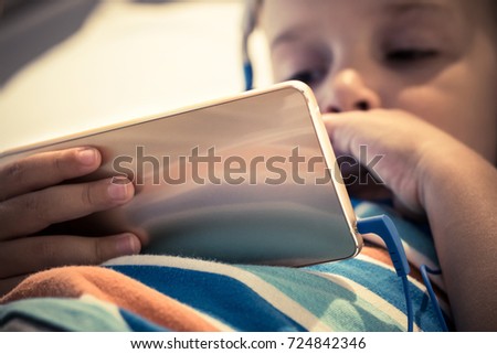 Close up of boy using smart phone and watching cartoons. Kid surfing the internet on mobile phone.