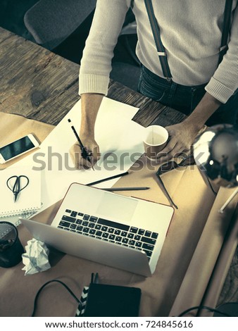 Vintage hipster wooden desktop top view, male hands using a laptop and holding a pencil