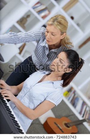 Woman teaching keyboard to female adolescent