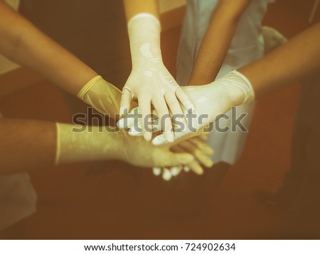 In selective of human hands in rubber glove stacked on blurred hand of teamwork ,The hands teamwork of medical team,classice old film design,vintage tone,blurry light design background