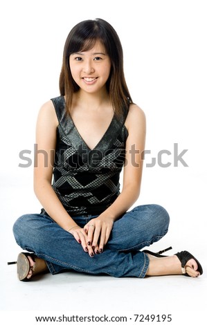 A cute young Asian woman in black and silver top and jeans on white background