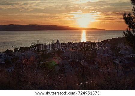 Sunset view of blue clear sea and the remote mountain range of popular touristic destination. Panoramic view of beautiful Croatian landscape with rolling hills, gardens and houses of the ancient town.