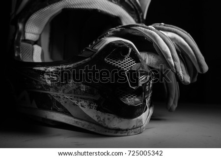 Motocross helmet and gloves. Black and white photography. Dirty motocross helmet. Moto equipment.