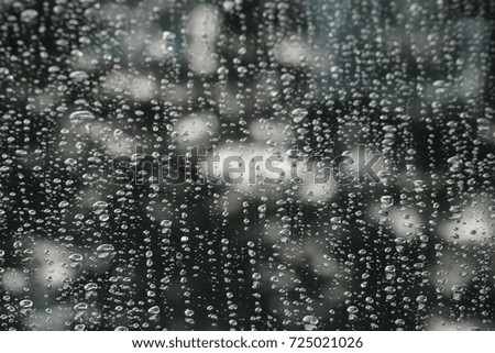 Droplet through windshield : cars, lights and rain in a green background.