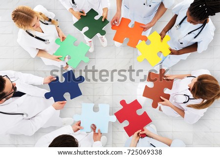 Elevated View Of Doctors Standing In Circle Holding Colorful Puzzle In Hospital