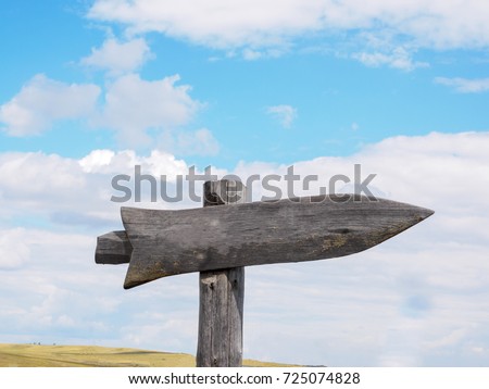 Empty wooden signpost with one arrows on the blue sky and clouds background.