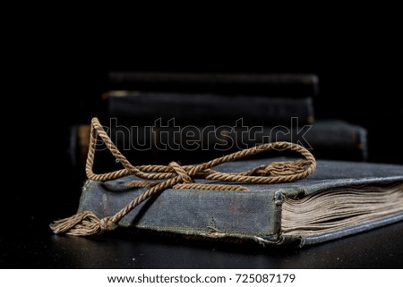 An old book lying on a black table. In the background a pile of old chunks. Black table, black background.