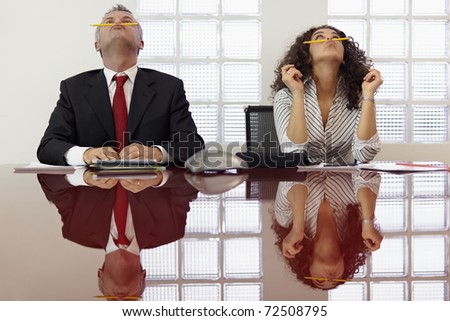 Bored businessman and secretary playing with pencil and having fun in office meeting room. Horizontal shape, front view, waist up