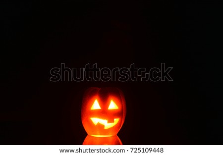 Pumpkin with cut eyes and mouth with a candle inside on a dark background - a symbol of Halloween