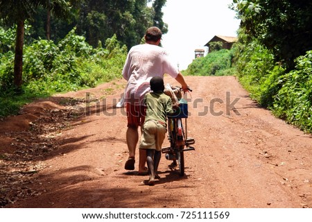 Uganda boy and foreigner man walking with bicycle to the hill in Jinja town , Uganda