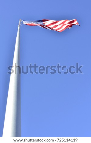 American flag blowing in wind at top of tall flag pole