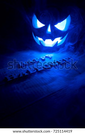 Halloween concept. Background of the holiday mystical pumpkin, jack lantern, in the dark with icy blue light and smoke with the letters Trick and Treat
