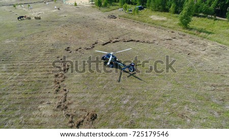 Helicopter lands in a field. Helicopter in the middle of green field prepare to fly. Helicopter arrived on field