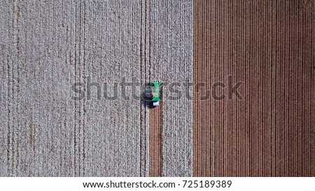 Aerial view of a Large green Cotton picker working in a field. Royalty-Free Stock Photo #725189389