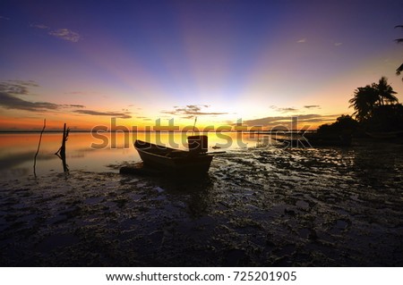 The Majestic sunrise of the seascape with morning rays and fisherman boat as point of interest. motion to sky and vibrant color. 