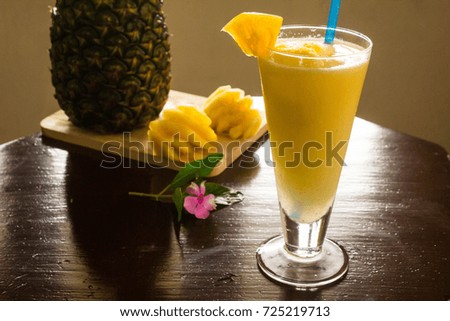 Pineapple smoothie in glass with purple flowers and pineapple slices on the table is brown, a drink with health benefits Maw thirst for summer.