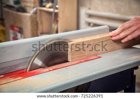 Close-up of a man sawing a piece of wood on the circular saw in hand flying sawdust Royalty-Free Stock Photo #725226391