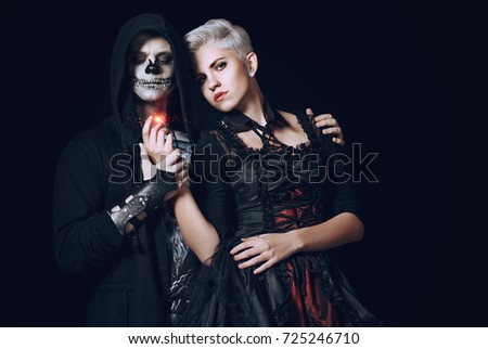 Halloween couple in gothic clothes. Fashion models posing on black background. Halloween make-up. Toned image.