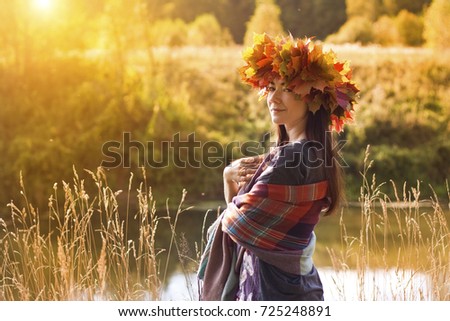 Beautiful woman with wreath of maple leaves in autumn forest on a sunny day. Great season picture with fall mood. Nature september and october composition.