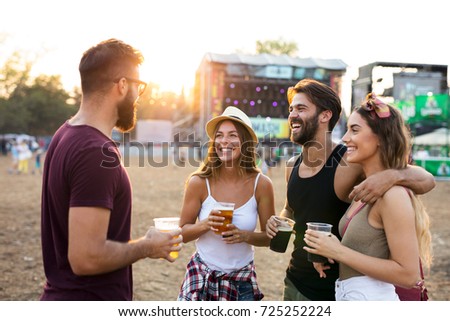 Young friends hanging out and enjoying drinks at music festival