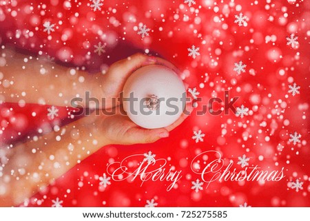 Merry Christmas background or gift card - child's hands holding white ornament on red background