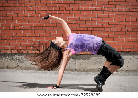 Beautiful teenage girl dancing hip-hop over red brick wall