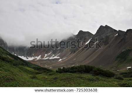 a picture of a landscape of mountains. Mountain to the clouds. High mountain. Summer photography. The greens grow around the mountains. Lake in a mountain valley