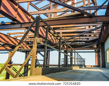 modern frame work of metal construction carcass roof support of building. rusty metal beam of warehouse or factory against blue sky. 