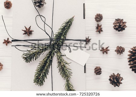 christmas present flat lay. stylish white christmas gift with empty tag and anise tree branches pine cones on rustic background top view, space for text. xmas seasonal greetings. winter holidays